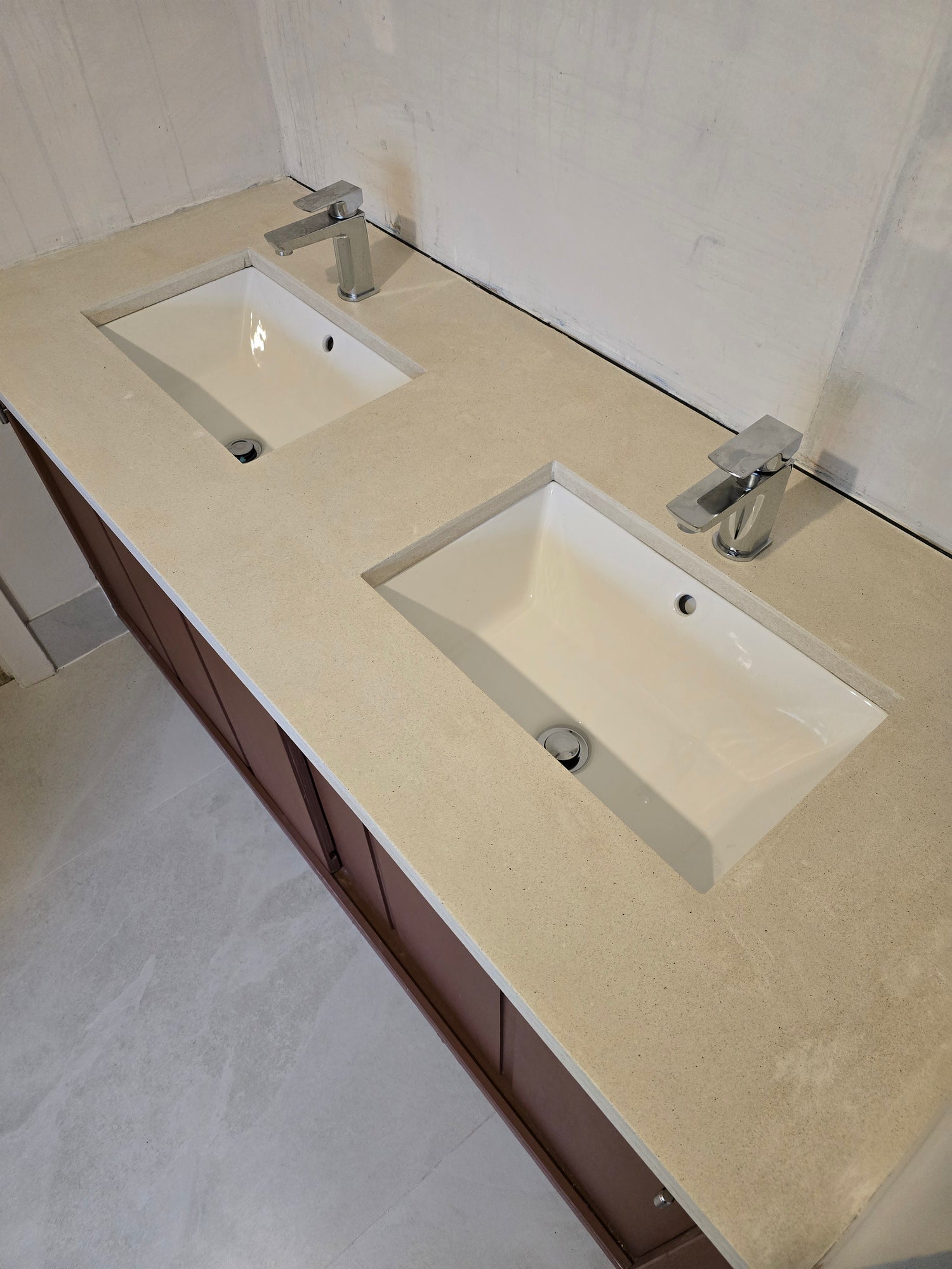 Bathroom vanity with two square undermount sinks on a light-colored countertop.