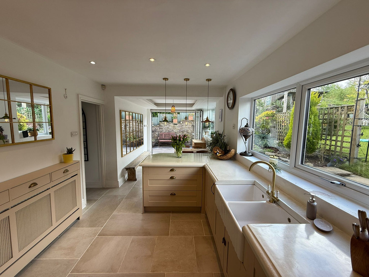 Modern kitchen with large windows, white cabinets, and a tiled floor.