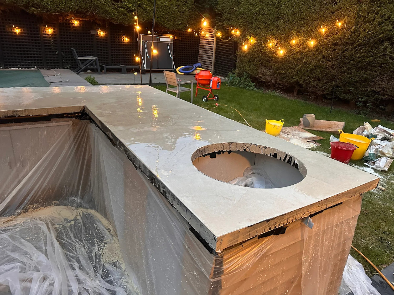 Outdoor kitchen counter under construction with tools and materials in a backyard setting.